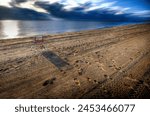 Early morning beach scene with chair and footprints in the sand