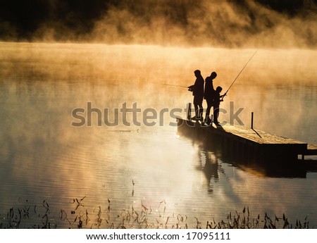 Early morning fishing in autumn on a lake as the mist rises from the water.