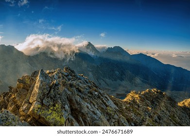 Early morning in High Tatras mountains, Slovakia. An amazing view of high rocky peaks surrounded by clouds during golden hour. Sunrise over High Tatras mountains from the top of Koprovsky peak. - Powered by Shutterstock