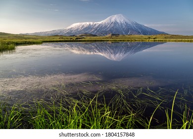 Early in the morning in Klyuchevskoy Park near the lake, the Plosky and Ostry Tolbachik volcanoes in a mirror image - Shutterstock ID 1804157848