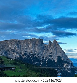 The early morning light reveals the stunning contours of the Dolomites in South Tyrol. A cable car station is visible in the foreground, inviting visitors to explore. - Powered by Shutterstock