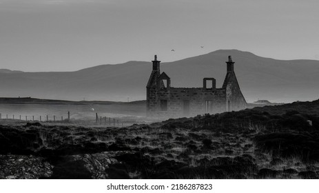 Early morning mist rising above the moorland with a derelict abandoned house ruins. Mountains in the background and birds flying over the ruins. Black and white landscape photo. - Powered by Shutterstock