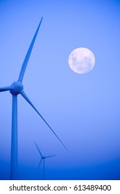 Early morning mist at wind farm, tungsten processed, moon in shot. Concepts of turbines working all hours.