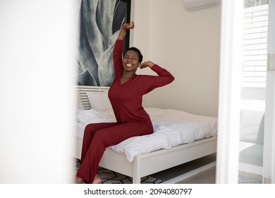 Early Morning Routine Of Beautiful  African Woman Stretching Arms Outwards While Sitting On Bed, With Copy Space