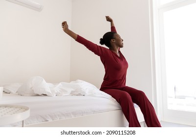 Early Morning Routine Of Beautiful Black African Woman Stretching Arms Outwards While Sitting On Bed, With Copy Space