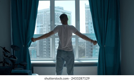 Early morning, silhouette of man exercising, stretching body by window at home. Media. Rear view of a young man standing against window. - Powered by Shutterstock