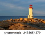 Early morning sunlight lights up the white stone lighthouse at Peggy