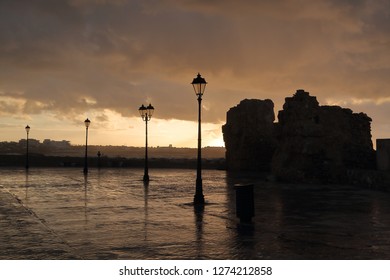 Early Morning View, Silhouette, After Rain At Shore In Pafos, Cyprus, Street Lamps, Rocks, Buildings At Horizon, Rainy Heavy Clouds In Sky, Reflections On Wet Ground