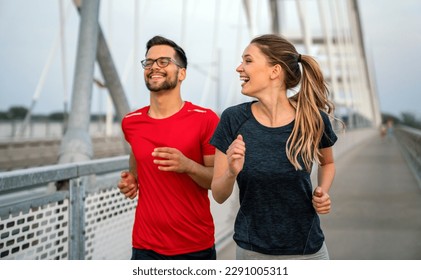 Early morning workout. Happy couple running across the bridge. Living healthy lifestyle.