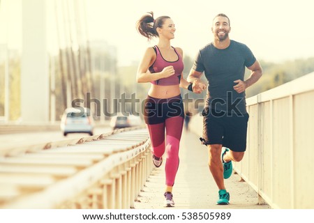 Early morning workout. Happy couple running across the bridge. Living healthy lifestyle. 