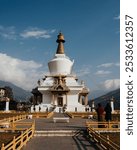 Early morning worship at the Memorial Stupa Chorten, a Tibetan Buddhist temple in Thimphu, Bhutan with mountains and blue skies.