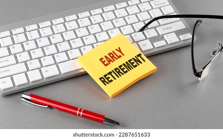 EARLY RETIREMENT text on a sticky with keyboard, pen glasses on a grey background