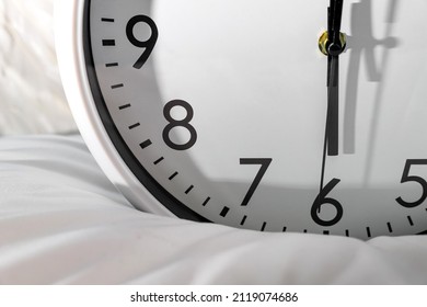 Early riser concept with a clock striking 6 a.m. An analogue clock on a pillow. Time-management background  