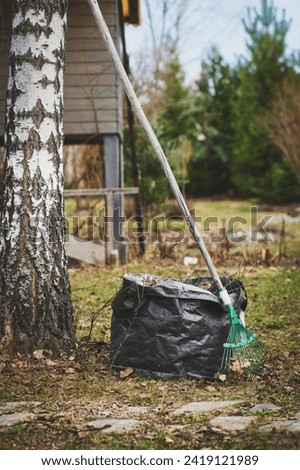early spring cleaning in garden. Raking leaves. Composting in bags. Seasonal yardwork.