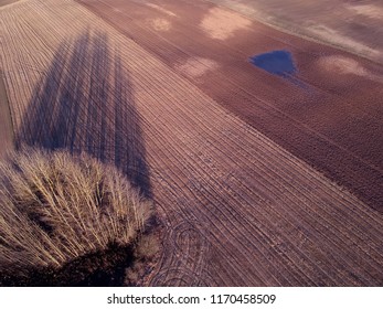 Early spring wet farmland fields with stubble and evening shadow, aerial view