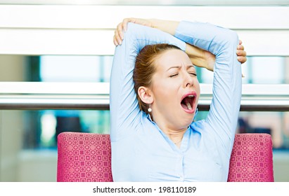 Its is too early for this meeting. Closeup portrait sleepy young business woman, sitting in armchair wide open mouth yawning, eyes closed, looking bored, isolated office windows background. Emotions - Powered by Shutterstock