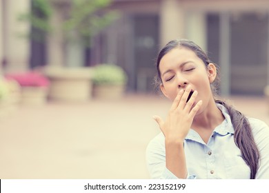 It Is Too Early For This Meeting. Portrait Sleepy Young Business Woman Covering With Hand Wide Open Mouth Yawning Eyes Closed Looking Bored Isolated Outside Office Background. Emotion Face Expression