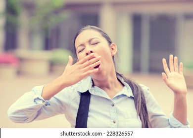 It Is Too Early For This Meeting. Portrait Sleepy Young Business Woman Covering With Hand Wide Open Mouth Yawning Eyes Closed Looking Bored Isolated Outside Office Background. Emotion Face Expression