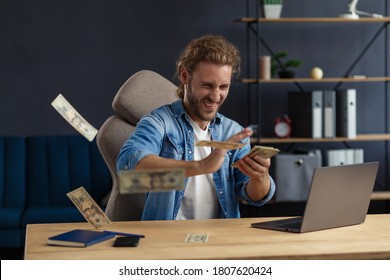 Earnings online. Win the money. I'm rich. Portrait of a young freelancer or businessman in a home office. Throws cash. Successful deal. - Shutterstock ID 1807620424