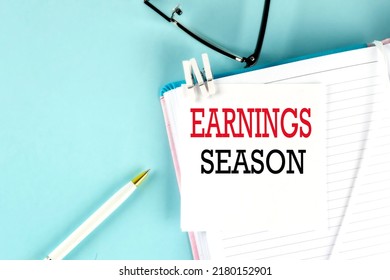 EARNINGS SEASON Text On Sticky On Notebook With Pen And Glasses , Blue Background