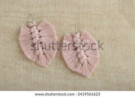 Earrings made with thread on a textile background. Handmade earrings.