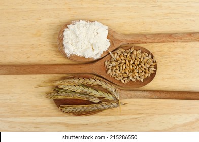 Ears And Grains Of Barley And Flour In Wooden Spoons On A Wooden Board