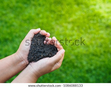 Eart day, save the earth, love concept. the woman hand holding a soil on green grass blur background.