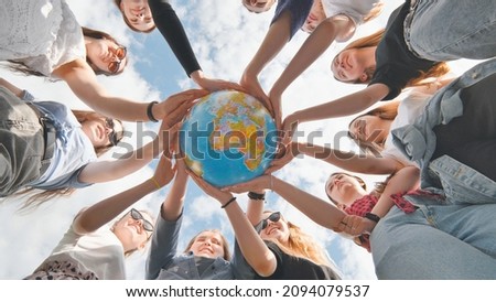 Earth conservation concept. 11 girls hug the earth globe with their hands.