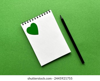 Earth Day, April 22, notepad and pencil on green background