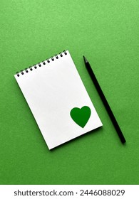 Earth Day, April 22, notepad and pencil on green background