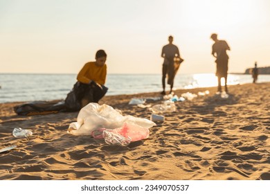 Earth day. Volunteers activists collects garbage cleaning of beach coastal zone. Woman and mans puts plastic trash in garbage bag on ocean shore. Environmental conservation coastal zone cleaning - Shutterstock ID 2349070537