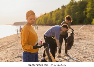 Earth day. Volunteers activists team collects garbage cleaning of beach coastal zone. Woman puts plastic bottle trash in garbage bag on ocean shore. Environmental conservation coastal zone cleaning - Powered by Shutterstock