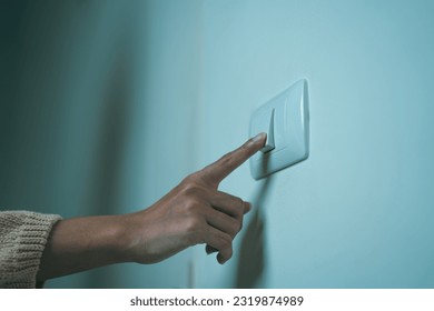 Earth Hour Close up woman finger turn off or on the light to saving electrical energy. Finger pushing light switch turn on or off. White switch - Shutterstock ID 2319874989