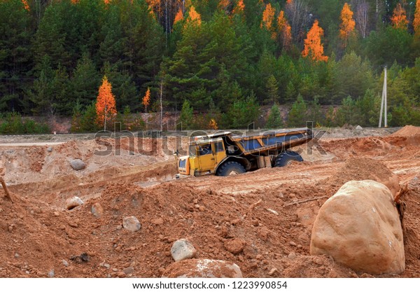Earth\
mover loading dumper truck with sand in quarry. Excavator loading\
sand into dumper truck.Quarry for the extraction of minerals. Large\
quarry dump truck. Production useful\
minerals.
