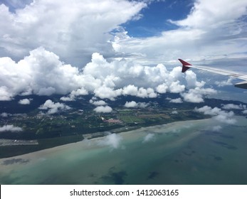 Earth, Ocean And Plane Wing View From Plane Window. Sea And Sky Top View On Plane. Aerial View Of Airplane Flying Above Shade Clouds And Sky.