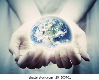 The earth shines in young woman hands. Concepts of save the world, protection, taking care, environment. Elements of this image furnished by NASA