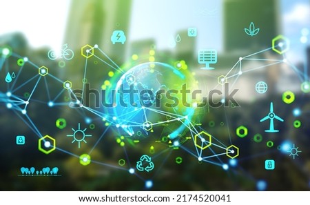 Earth sphere hologram and glowing eco hud with diverse icons and lines, blurred green city on background. Ecosystem and futuristic technology. Concept of green energy and renewable sources