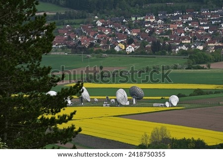 A tractor turns mown hay in a field in a small community