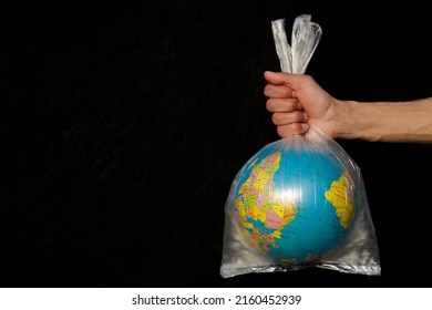 Earth Wrapped Up In Plastic Bag. Globe In A Plastic Bag. Concept Of Plastic Pollution Of The Earth. World Environment Day Concept. Copy Space. Save Earth Concept On Black Background Selective Focus