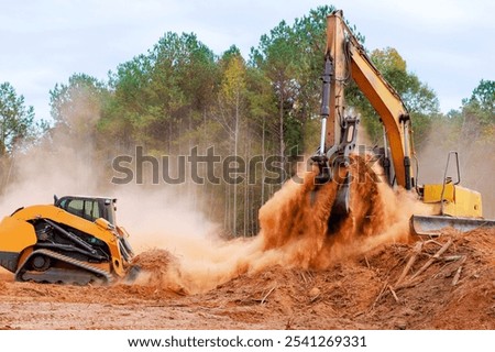 An earthmoving small mini tractor is leveling ground during construction during earthworks