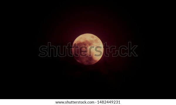 Earth\'s permanent natural satellite - the Moon On a\
black background.Halloween background .full moon dark cloud at\
night . Close up picture of Blood Moon surface textured of yellow\
full moon
