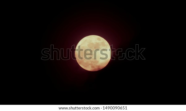 Earth\'s permanent natural satellite - the Moon On a\
black background.Halloween background .full moon dark cloud at\
night . Close up picture of Blood Moon surface textured of yellow\
full moon
