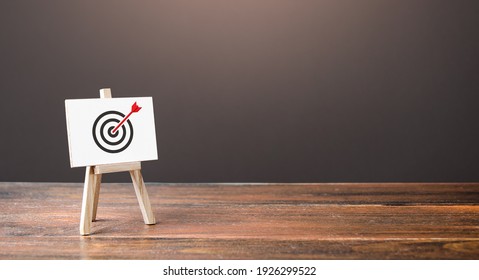 Easel with an arrow in target center. Direct hit, straight to the point. Marketing and targeting audience. Reached goal , best result. Complete success. Advertising strategy. Excellent job performance - Shutterstock ID 1926299522