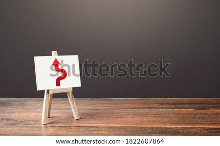 An easel with a red arrow avoiding an obstacle. Deviation from the route. Inevitability and inability to delay the inevitable. Purposefulness and perseverance, confident movement towards assigned goal