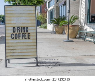 An Easel Sign For Coffee Sits On The Sidewalk In Front Of A Restaurant.