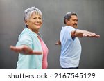 Easing into retirement with some yoga. Shot of a happy older couple practicing yoga together outdoors against a gray background.