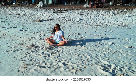 An East Asian Girl Meditating On The Sandy Beach In Gili Meno, Lombok, Indonesia