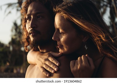 An East Asian Man Looks Into The Distance And Behind Him Stands A Girl And Hugs Him By The Neck. High Quality Photo