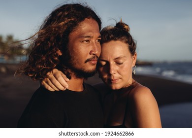 An East Asian Man Looks Into The Distance While The Girl Hugs Him With Her Hand By The Neck And Snul Her Cheek Closing Her Eyes. High Quality Photo