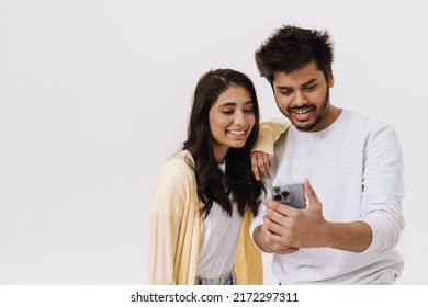 East Asian Young Man And Woman Smiling And Using Cellphone Together Isolated Over White Background